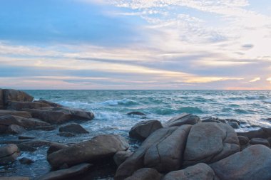  Sahilde batan güneş sırasında rüzgar serin eser. Kumlu zeminile güzel bulutlar ve kayalar