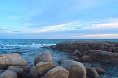 Batan güneş sırasında sahilde rüzgar serin eser. Kumlu zeminile güzel bulutlar ve kayalar