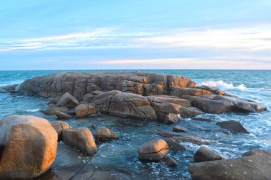 Batan güneş sırasında sahilde rüzgar serin eser. Kumlu zeminile güzel bulutlar ve kayalar