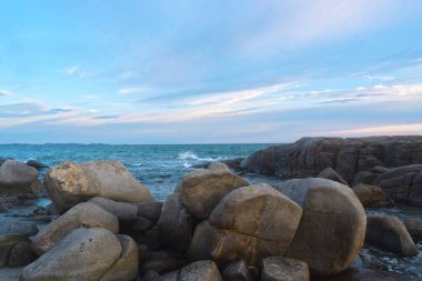 Sahilde batan güneş sırasında rüzgar serin eser. Kumlu zeminile güzel bulutlar ve kayalar