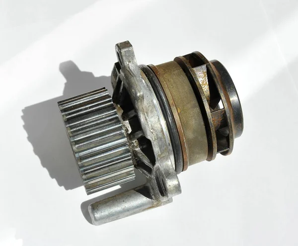 Closeup of a car engine cooling system pump on a white background. Working, natural, metal pump engine cooling system of the car. Plastic impeller pump. Spare part of the car engine.