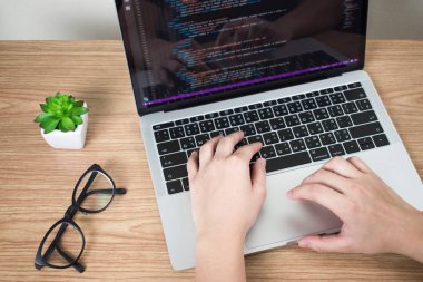 Programcıların elleri dizüstü bilgisayar ekranında kod yaratıyor.