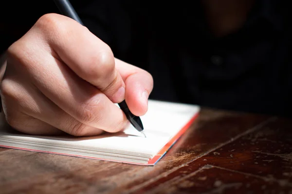 Mão Está Escrevendo Livro Uma Mesa Madeira Perto Uma Janela — Fotografia de Stock