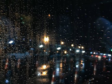 Gece mavi cam arka plan üzerinde yağmur Damlaları, arabadan ışık.