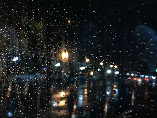 夜の青いガラスの背景に雨の滴 車からの光 — ストック写真