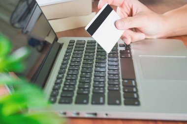 Bir adam mavi ekose gömlek bilgisayarlarda alışveriş giymek ve kredi kartı ile ödeme.