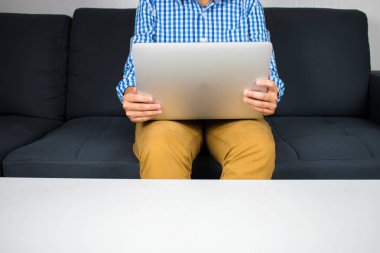 Kanepeüzerinde çalışan mavi ekose gömlek giyen bir kişinin eli.