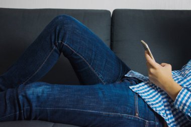 İnsanlar kanepede telefon oynarken yatıyorlar..