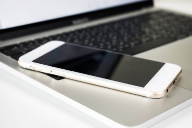 Dizüstü bilgisayar masasındaakıllı telefonun görüntüsüne yakın çekim.