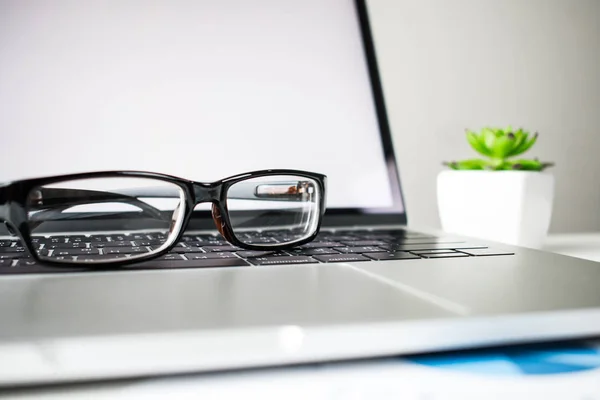 Close-up to the eye glasses on the laptop on the white desk.