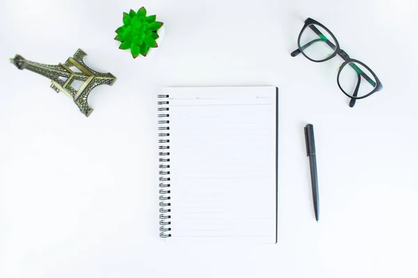 White office desk table with blank notebook, laptop and small pl