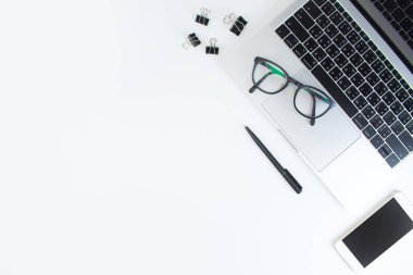 Beyaz masada dizüstü bilgisayar, gözlük ve akıllı telefon ile çalışma alanı