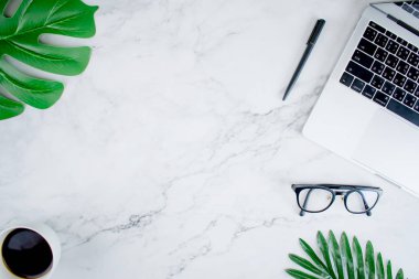 Dizüstü bilgisayar, gözlük, kalem ve moder yaprakları ile Mermer üst görünümü