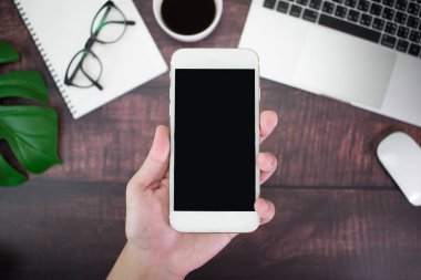 Yakın, ahşap ta üst görünümünde bir akıllı telefon tutan el