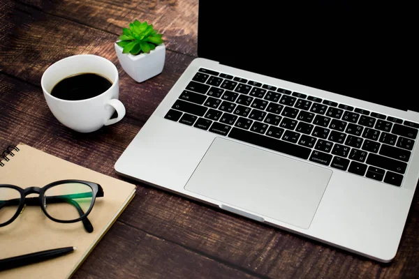 Ahşap bir masada dizüstü bilgisayar maketile modern çalışma alanı tasarımı.