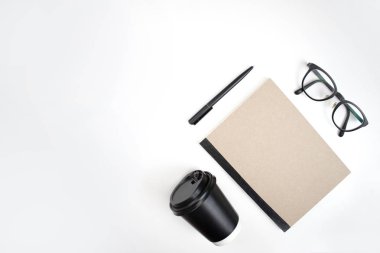 Üstteki görünüm, defter, kalem, gözlük ve beyaz bir sırtüstü kahve