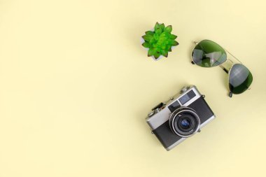 Sarı arka planda film kamerası ile güneş gözlüğü. Üst v'de