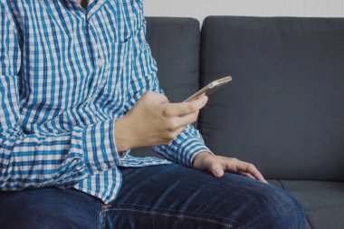 Asyalılar kanepede akıllı telefon kullanıyor. Kopya ile