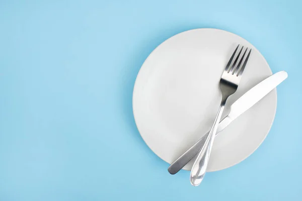 Top view plate with a spoon on the blue background. — Stock Photo, Image