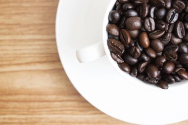 Fotokopi alanı olan ahşap bir arka planda bardaktaki kahve çekirdekleri., 