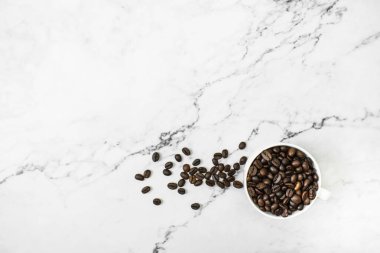 Brown coffee beans with coffee on a marble background with copy 