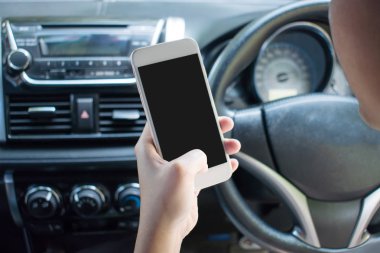 Araba sürerken akıllı telefon kullanan bir elin yakın plan görüntüsü.