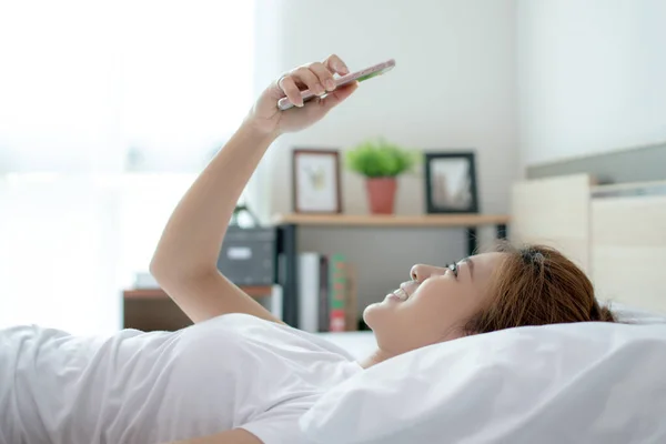 Ευτυχισμένη Ασιάτισσα Γυναίκα Χρησιμοποιεί Ένα Smartphone Και Είναι Ξαπλωμένη Στο — Φωτογραφία Αρχείου