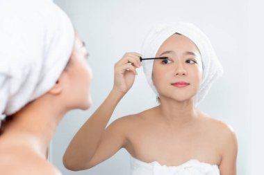 Asyalı güzel kadınlar büyük bir aynanın önünde siyah maskara kirpikleri sürüyorlar..