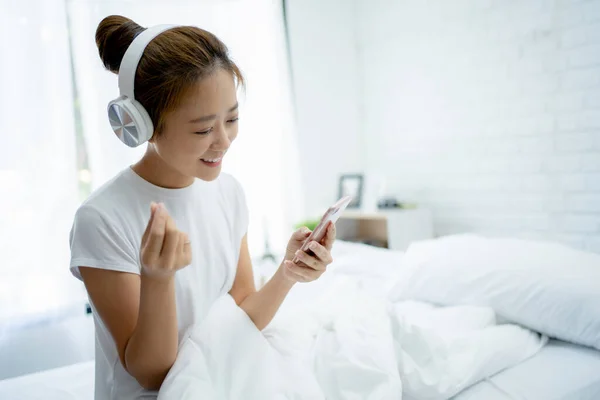 若い女性の音楽を聞いて 部屋で歌う 彼女は彼女の携帯電話のアプリを使用して彼女の好きな曲を聞きます — ストック写真