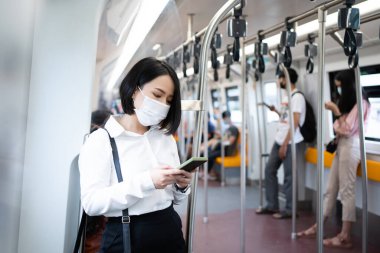 Genç Asyalı kadın yolcular Covid19 salgınında büyük bir şehirde seyahat ederken metroda maske takıyorlar..