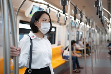 Metroda maske takan Asyalı bir kadın. Coronavirüs salgını, salgını ve salgını olan büyük bir şehirde seyahat ediyor..