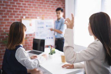 Asyalı işadamları ofiste grafikleri açıklar ve bir kadın soru sormak için elini kaldırdı..