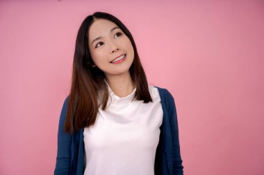 Stüdyoda pembe arka planda bir şey düşünen Asyalı kadın..