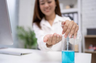 Genç bir kadının eli ofiste alkol jölesine basıyor..