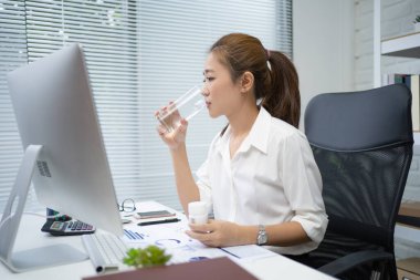 Genç çalışan kadın ofisinde ilaç alıyor ve su içiyor. O hasta..
