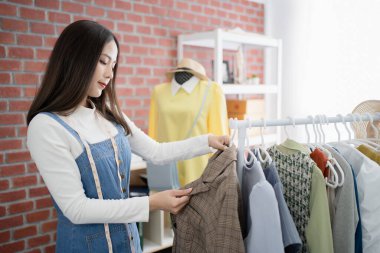 İnternette kıyafet satan genç Asyalı iş kadını dizüstü bilgisayarla canlı yayın yapmadan önce hisse senetlerini kontrol ediyor..