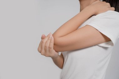Bir arabacının vücudunda acı. Asyalı kadının dirsek ağrısı var. Dirsek dirsek ağrısına el ele tutuşuyor. Ağrının yerini gösteriyor.