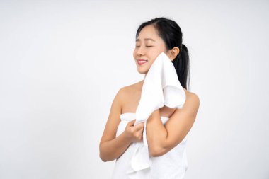 Asyalı genç bir kadın beyaz havlu kullanıyor. Yüzünü temizliyor. Temiz, kuru bir ten.