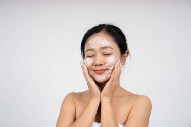 Genç Asyalı kadın yüzüne nemlendirici krem sürüyor. Cilt bakımı kavramı