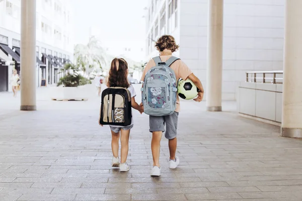 Frères vont à l'école avec leurs sacs à dos et un ballon de football . — Photo