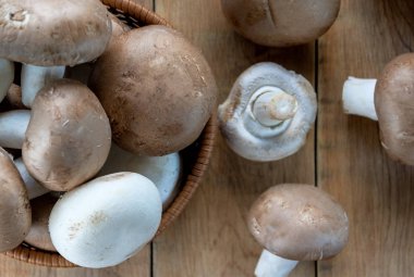 Champignons, hasır sepet ve ahşap masada mantar