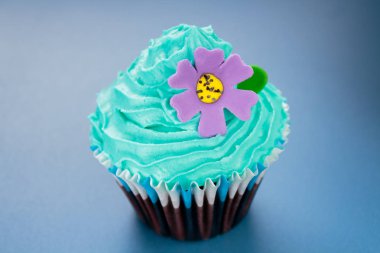 Mavi krema ve mor çiçek ile Cupcake