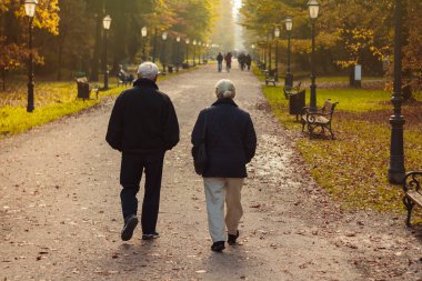 Emekli yaşlı çift sonbaharda parkta yürüyor