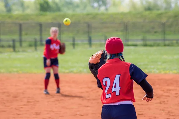 Softball girl players passing the ball