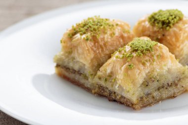 Beyaz tabakta antep fıstığı ve cevizli baklava. Sığ alan derinliği