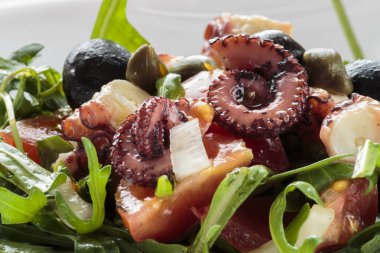Beyaz tabakta rucola ve zeytin ile ahtapot salatası
