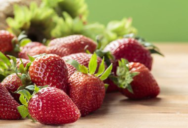 Yeşil arka plan ile ahşap tahta üzerinde kırmızı çilek yığını