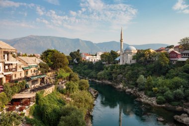 Mostar, Bosna-Hersek - 15 Ağustos 2015: Mostar'daki Eski Köprü'den Neretva nehri, restoranlar ve camiye manzara
