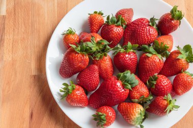 Beyaz plaka üzerinde kırmızı çilek yığını, kopya alanı