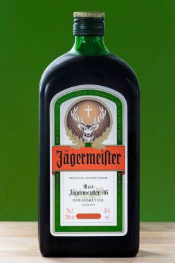 Zagreb, Hırvatistan - 06 Nisan 2015: Ahşap masa üzerinde yeşil arka planlı bir şişe Jagermeister. Jagermeister 56 farklı bitki ve baharatla yapılan bir Alman alkollü içkisidir..